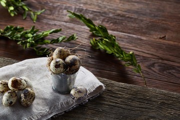 Spring composition of quail eggs in bucket on a linen napkin and boxwood branch, selective focus
