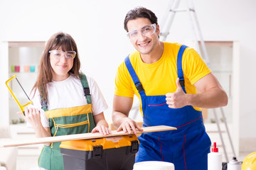 Man explaining woman woodworking tips in wood workshop