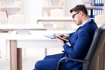 Young handsome businessman employee working in office at desk