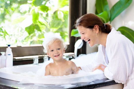 Mother washing baby in bubble bath. Water fun.