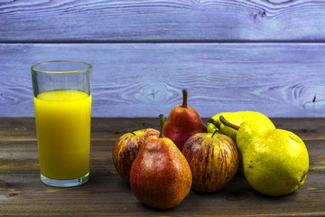 A glass of freshly squeezed orange juice. Twigs of mint and slices of lime and two pears.