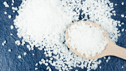 Coarse sea salt on dark background. Top view.