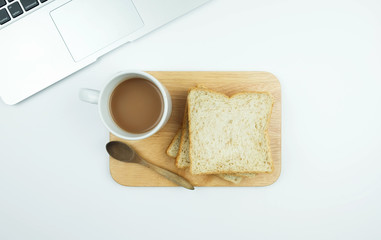 Sliced Whole wheat bread and a cup of coffee on Chopping Wood and laptop on a white background.
