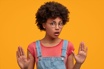 Discontent African American female makes stop sign with palms, disagrees to do something,...