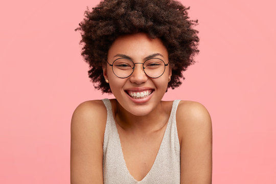 Cropped shot of pleased attractive African American female with positive smile, being in good mood as has party with friends, enjoys leisure time. People, happiness and positiveness concept.