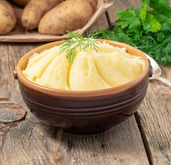 Mashed potatoes, boiled puree in brown bowl on dark wooden rustic background, side view
