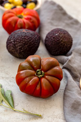 Tomato on concrete tabletop with other vegetables blurred.