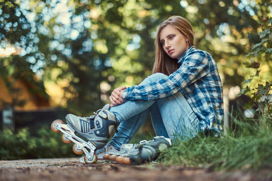 Beautiful woman in a fleece shirt and jeans resting after roller skating.