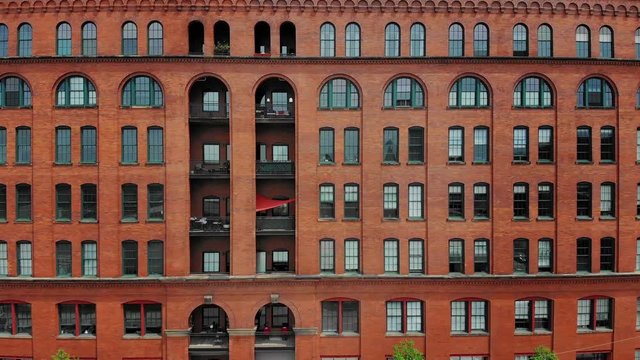 An aerial profile side view of a red brick apartment building in Pittsburgh's Strip District neighborhood.  	