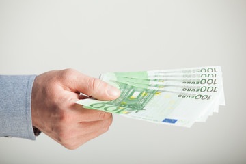 Man's hand extending euro banknotes