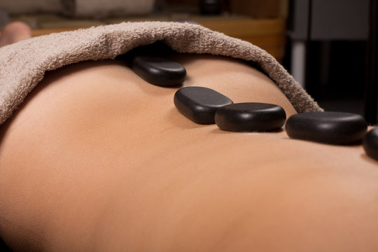 Massage Woman lying with spa stones at her back