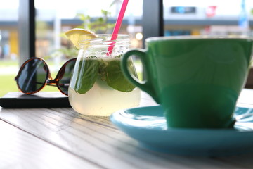 Blue and Green cup of coffee and lemonade on a white wooden table