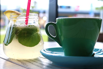 Blue and Green cup of coffee and lemonade on a white wooden table