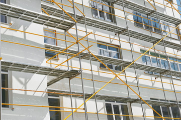 scaffolding near a new house, building exterior, construction and repair industry, white wall and window, yellow pipe