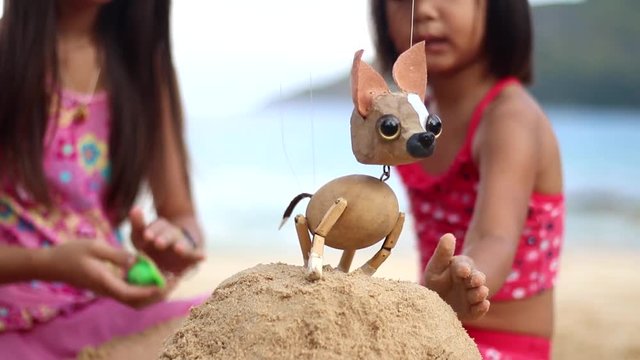 Sister and sister are playing at the beach with the chihuahua puppet
