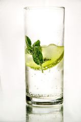 Isolated glass of cold fresh water with bubbles, lime, ice and mint on white background. Healthy life concept