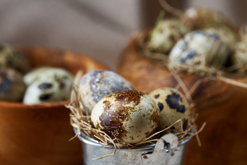 Quail eggs in a wooden bowl on a homespun tablecloth, top view, close-up