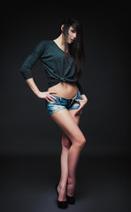 Studio fashion shot: portrait of seductive young girl in denim shorts and blouse. Model test