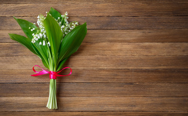 Lily flower bouquet tied with red ribbon on wooden retro background with copy space