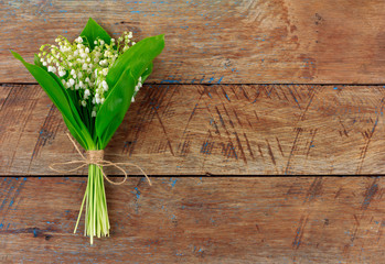 Lily of the valley flower bouquet tied with twine on wooden retro grunge background with copy space