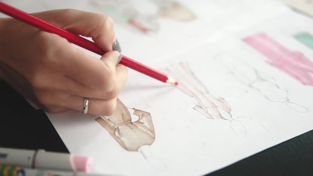 designer of clothes makes an outline of clothes with a felt-tip pen. female hands closeup