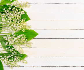 Lily of the valley flowers on white wooden background with copy space