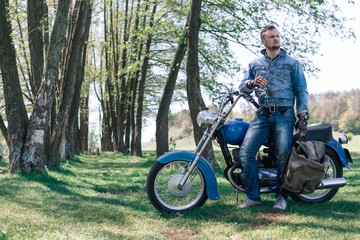 Portrait young guy with sunglasses and Jeans jacket and pants posing sitting on his vintage retro...