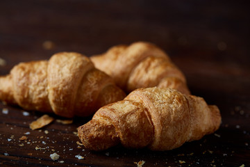 Tasty buttery croissants on an old wooden table, close-up, selective focus, shallow depth of field.