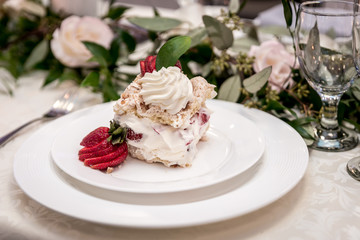 Obraz na płótnie Canvas vanilla and strawberry cake desert with beautiful background of flowers and green leaves set in a luxury plate for a banquet 