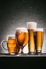 close up view of mugs of beer with froth on grey background