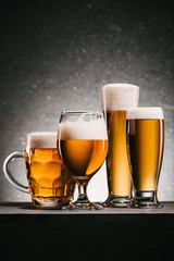 close up view of mugs of cold beer with foam on grey background