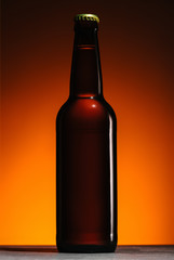 close up view of beer bottle on orange background