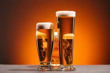 close up view of arrangement of glasses of beer on orange backdrop