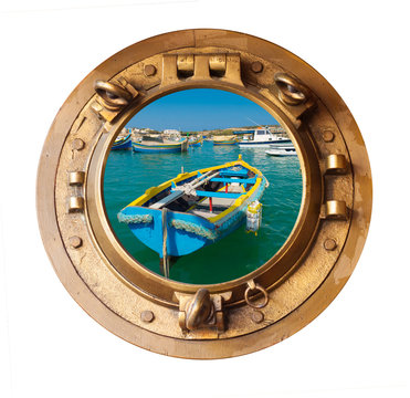 brass porthole and sunlit maltese rowing boat
