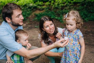 Fototapeta premium Happy family having fun in the park.Cute Little girl trying to inflate the soap