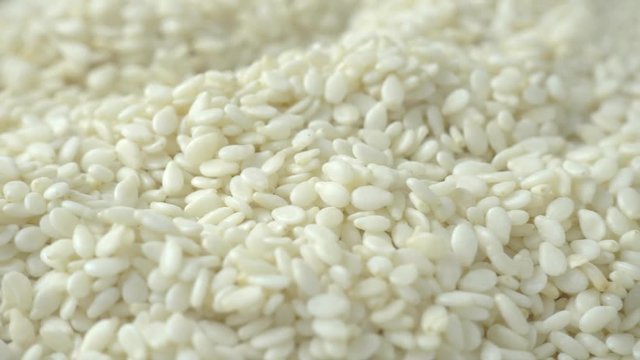 Rotating of white sesame seeds, close-up, top view, 4K