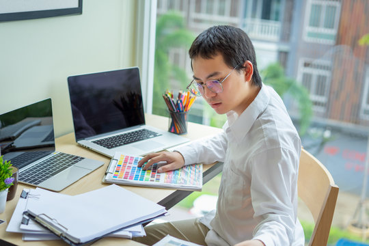 Young designers teamwork working with color samples for selection on office desk,Architects choosing color samples for design project,Black screen laptop for graphic montage.