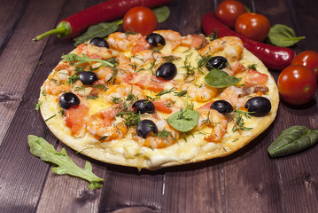 Traditional hot Italian pizza with seafood on wooden table. Only taken out of the oven.