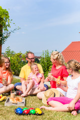 Fototapeta premium Happy family having picnic in garden front of their home