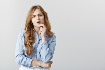 Trendy girl having doubts about new dress. Studio shot of disbelieving good-looking female student...