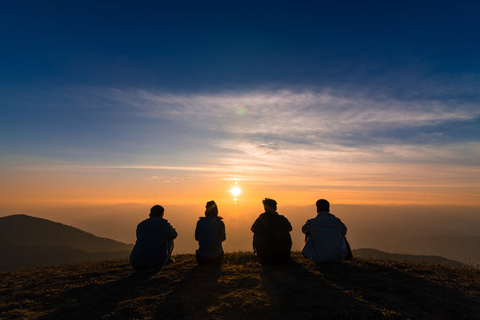 silhouette of friends  sitting together watching sunset for business successful and team work concept