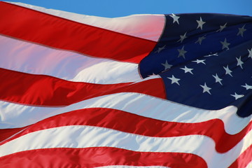 Close Up on American Flag Stars and Stripes Waving against Blue Sky in Afternoon Sun