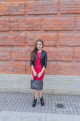 girl in dress and leather jacket on brick wall background