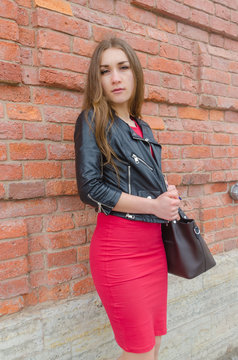 girl in dress and leather jacket on brick wall background