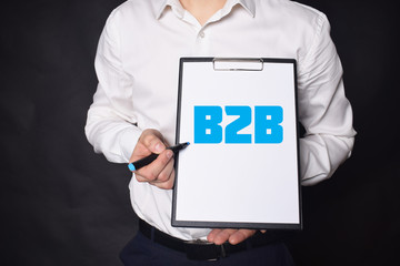 In the hands of a businessman a notebook with the inscription:B2B