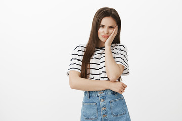 Feeling insult, puffling out cheeks from jealousy. Upset offended attractive caucasian woman, holding palm on cheek, frowning, being disappointed when boyfriend forbid go party with girlfriends