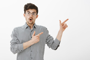 Boyfriend asks permission to go with guys. Portrait of excited ordinary european male model with beard and moustache, pointing with finger guns right and talking, suggesting go in direction