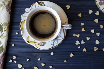 A cup of coffee with decor on a dark blue wooden table top view. 