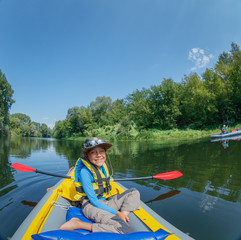 Happy boy kayaking on the river on a sunny day during summer vacation