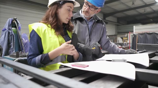 Metalworker and engineer meeting in factory